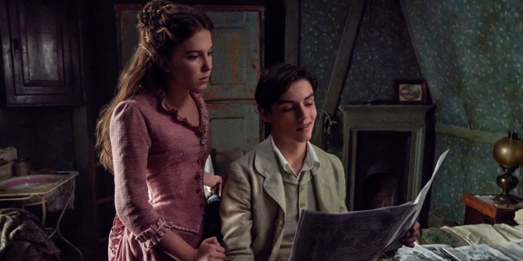 A young woman in a vintage dress looks thoughtfully at a young man sitting beside her. He is reading a newspaper in a room with rustic decor and muted tones.
